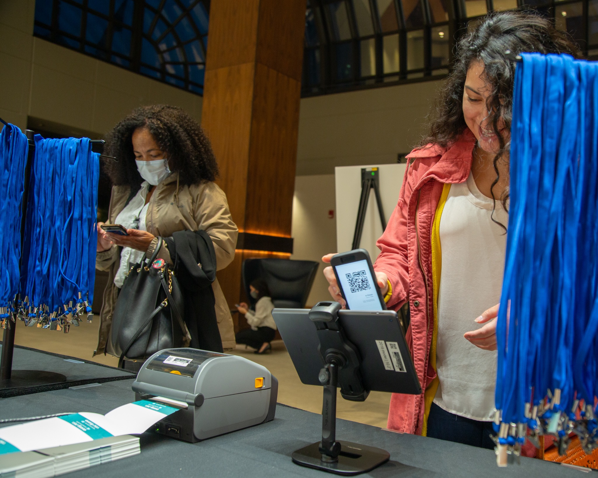 A person using an ipad to scan a QR code from their phone to check in to an event.