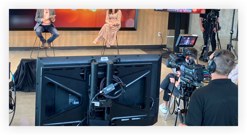 Picture of the stage at a hybrid event with cameras and confidence monitors set up around it.