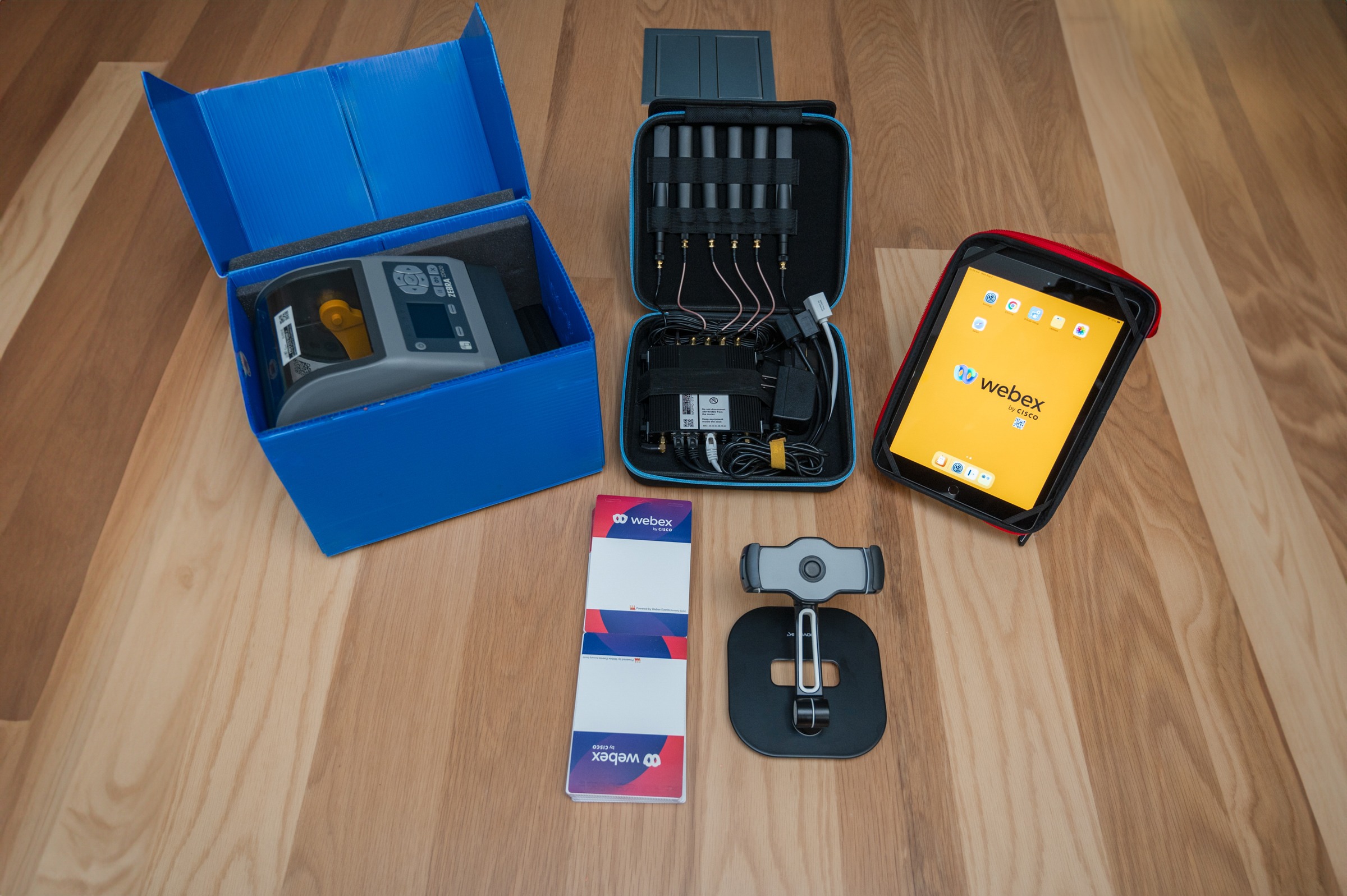 A choose 2 rent kit containing a badge printer, badges, chords, and ipad, and an ipad stand.