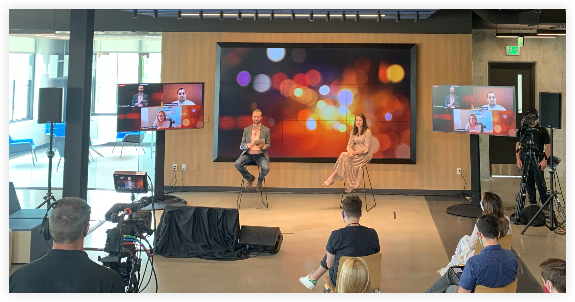 The stage at a hybrid event. Cameras and video boards with remote presenters are visible.